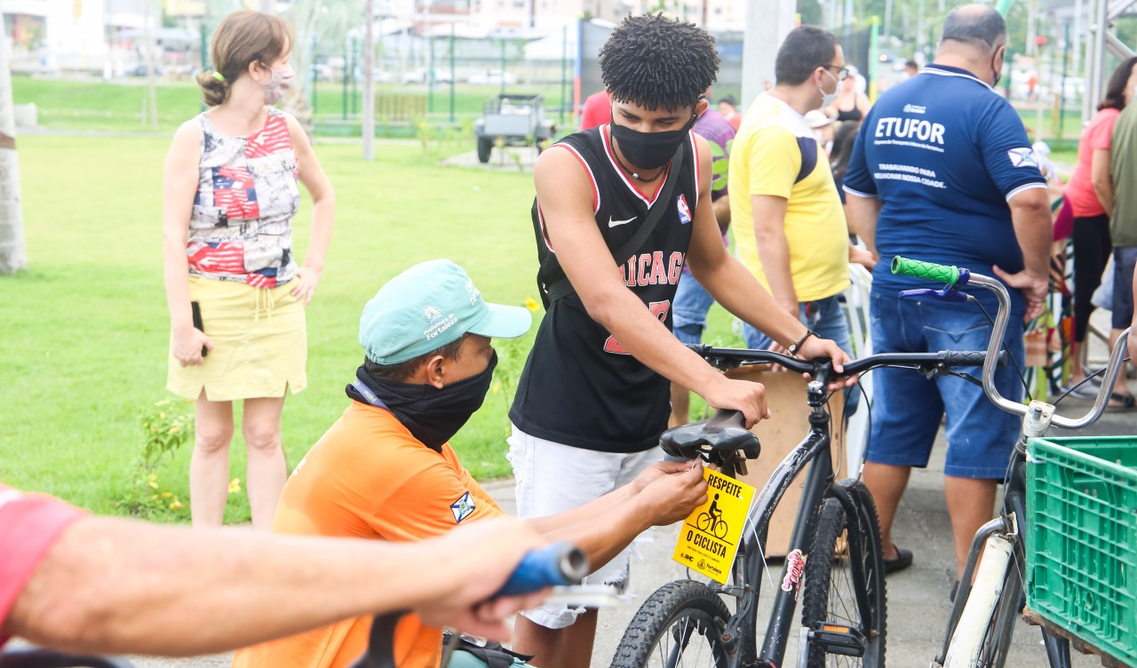 agente da amc coloca plaquinha de respeito aos ciclistas numa bike